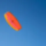 A vibrant sport kite soaring against a clear blue sky