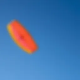 A vibrant sport kite soaring against a clear blue sky