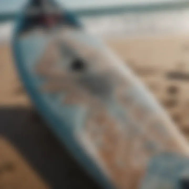 A close-up of a kiteboard with intricate designs resting on the beach